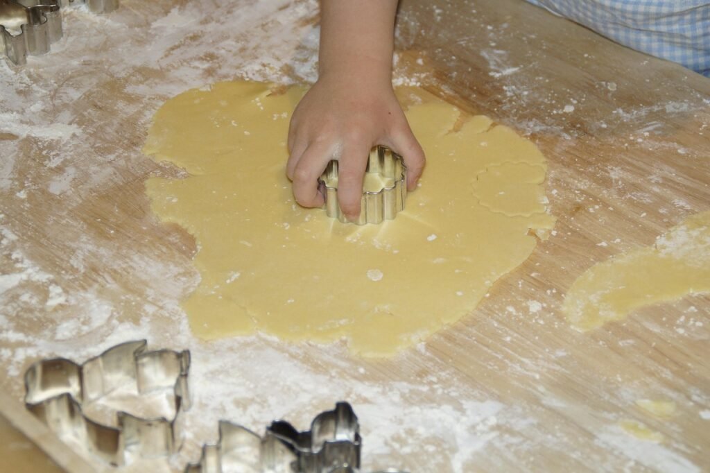 Main d'enfant qui découpe une forme à l'emporte-pièce dans la pâte