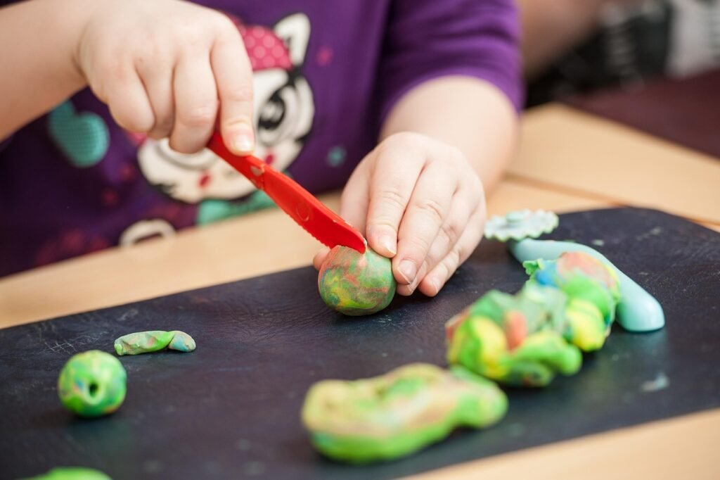 Petit enfant qui modèle de la pâte à modeler colorée